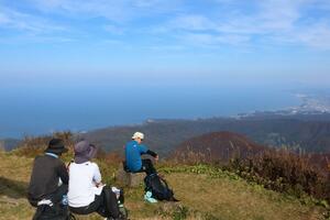 好天に恵まれた米山の山頂で休憩する登山者たち