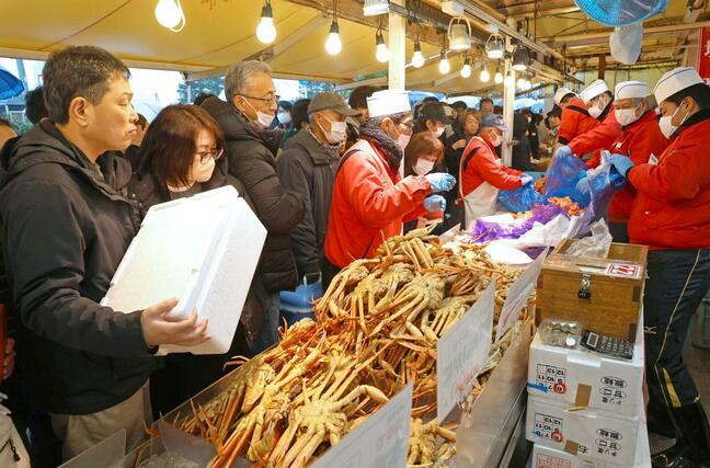 店頭に並んだカニを品定めする買い物客＝３０日、長岡市寺泊下荒町