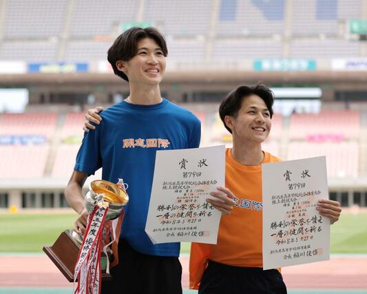 男子1500メートルで優勝した椿瑠偉音(開志国際・左)が表彰状を受け取り笑顔を見せる=デンカビッグスワン
