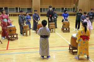 新井南小児童の手ほどきで和太鼓に挑戦する台湾の小学生=妙高市除戸の新井南小