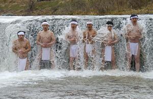名立川の冷水に打たれながら心身を清める参加者ら=3月20日、上越市名立区