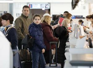 羽田空港の国際線出発ロビーで手続きをする訪日客ら=18日午前