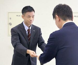 林業分野で初となる県地域おこし協力隊の任命書を受け取る石崎琢磨さん(左)=8月1日、県庁