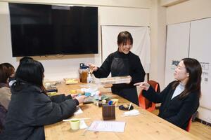 「居なりすん」参加者にいなりずしを配る佐々木茉歩さん(中央)=長岡市渡里町