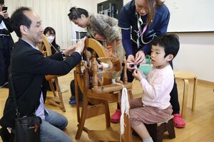 糸車を使って毛糸を紡ぐ子どもたち＝新潟市南区の市アグリパーク