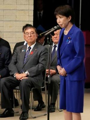 自民党総裁選後に開かれた両院議員総会に出席した石破首相。右はあいさつする高市早苗新総裁=4日午後3時2分、東京・永田町の党本部