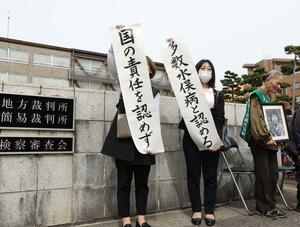 判決を受け「国の責任を認めず」「多数水俣病と認める」と報告する原告支援者ら=4月18日午後1時30分過ぎ、新潟市中央区の新潟地裁前