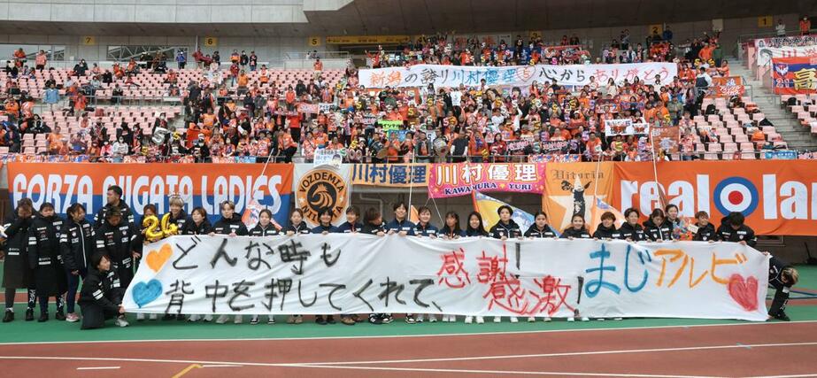 セレモニー後に横断幕を持ちサポーターと集合写真を撮る選手ら＝５月９日、デンカビッグスワンスタジアム