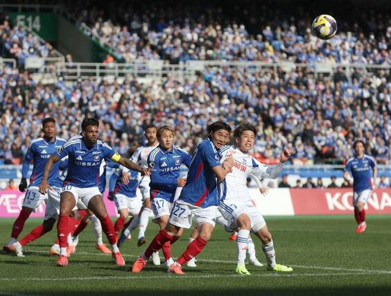 競り合う選手たち=日産ス