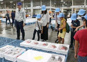 水産物の競りが行われる現場を見学する親子=新潟市江南区茗荷谷