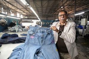 トランプ関税の影響下でも生産を続けるデニム工場で製品を手にする幹部=7月、レソトの首都マセル(共同)