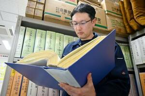 　身元特定に関する資料を読む京野祐也班長＝２月、宮城県警本部