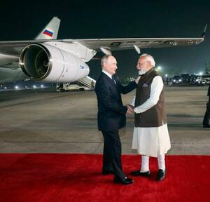 インドのモディ首相(右)と握手するロシアのプーチン大統領=4日、ニューデリー(インド外務省提供、共同)