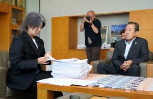 早期辞職を求める署名を受け取り、確認する静岡県伊東市の田久保真紀市長。右は元市議の浜田修一郎さん=27日午前、伊東市役所