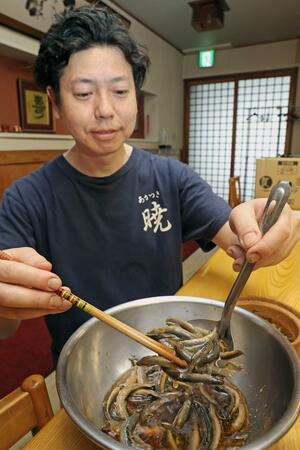 下味を付けたドジョウをすくう暁の桑原大祐さん=11日、新潟市中央区