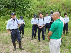 水不足で作付けできなかった田んぼで生産者(手前)から話を聞く上越市議たち=上越市牧区