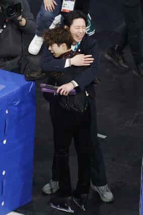 男子フリー演技を終え、日下匡力コーチ（奥）に迎えられる佐藤駿＝ミラノ（共同）