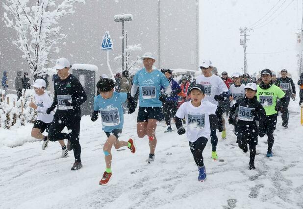 路面が雪で覆われた悪条件の中、勢いよくスタートするランナー＝１月１日、三条市