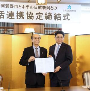 包括連携の協定書を手にする加藤博幸・阿賀野市長（左）と栗山敏昭・ホテル朱鷺メッセ社長＝新潟市中央区