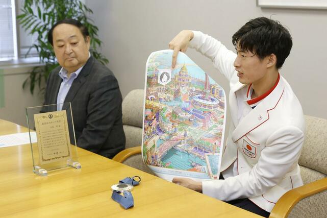 パリ五輪で贈呈されたポスターについて説明する古俣聖選手(右)=9月30日、新潟市役所