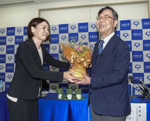 ノーベル生理学・医学賞の受賞が決まり、記者会見場で花束を受け取る大阪大の坂口志文特任教授(右)=6日、大阪府吹田市