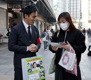 吉川友梨さんの情報提供を呼びかける大阪府警の警察官(左)=20日午後、大阪・難波