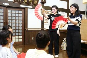 子どもに扇の扱い方を指導する九里多映さん(右)と池嶋菜央さん=柏崎市女谷