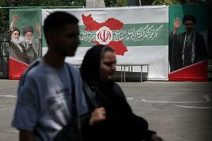 9日、イラン・テヘランで、前最高指導者アリ・ハメネイ師らの肖像のそばを通り過ぎる人々(WANA提供、ロイター=共同)