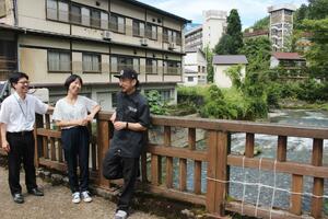 イベント会場となる合わせ湯橋の上で話す実行委員会のメンバー=魚沼市大湯温泉