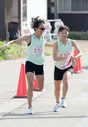 新潟北・teamTomozoAの4区石川桃子さん(左)がアンカーの篠澤葉さんにトップでたすきをつないだ第4中継所=2日、長岡市西片貝町