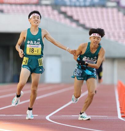 中越の１区丸山展（左）が２区波形泰良にタスキを渡す＝新潟市中央区