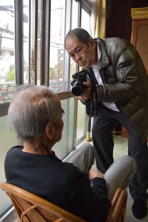 小嶺達雄さんを撮る山城博明さん=2月、名護市