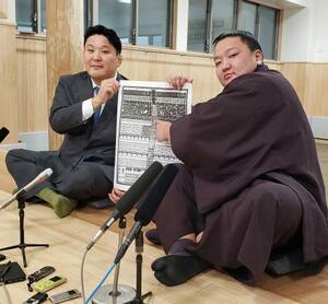 　大相撲初場所の番付表を手にする朝白龍。左は高砂親方＝２２日、東京都墨田区の高砂部屋