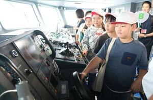 船のかじを取るハンドルを握る小学生=村上市岩船沖