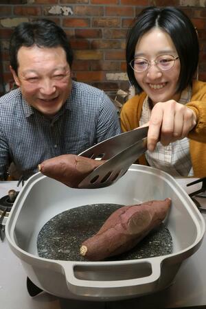 オークスの新商品「ナチュラルストーングリル」で石焼き芋を作る尾脇早英さん(右)と木村和男さん=三条市島田2