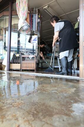 大雨で水に漬かった店舗を片付ける市民=3日、上越市中央1